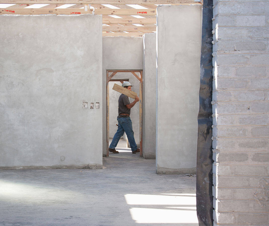 A man walking with a wooden plank in a construction site
